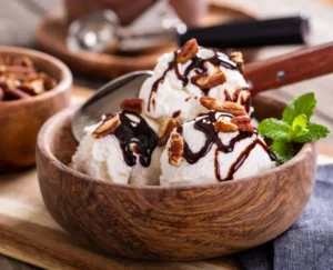 ice cream sundae wooden bowl closeup vanilla topped chocolate syrup pecans 142844302